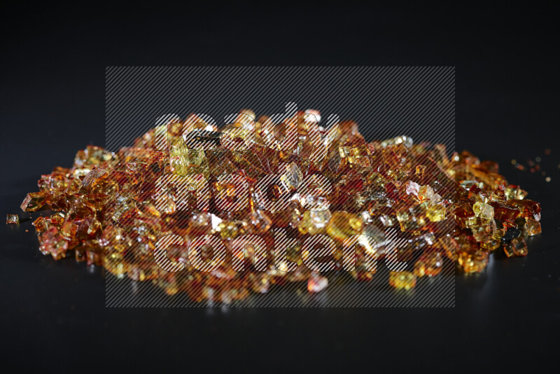 Transparent orange fragments of glass scattered on a black background