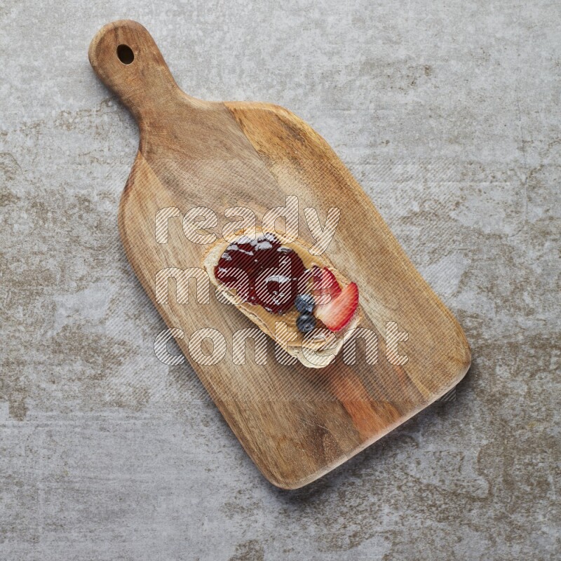 open faced peanut butter sandwich with jam, strawberries and blueberries & chia on a  grey textured background