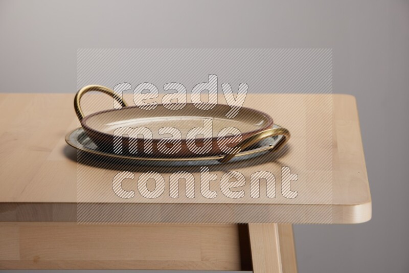 multicolored plate placed on a rounded stainless steel tray with golden handels on the edge of wooden table