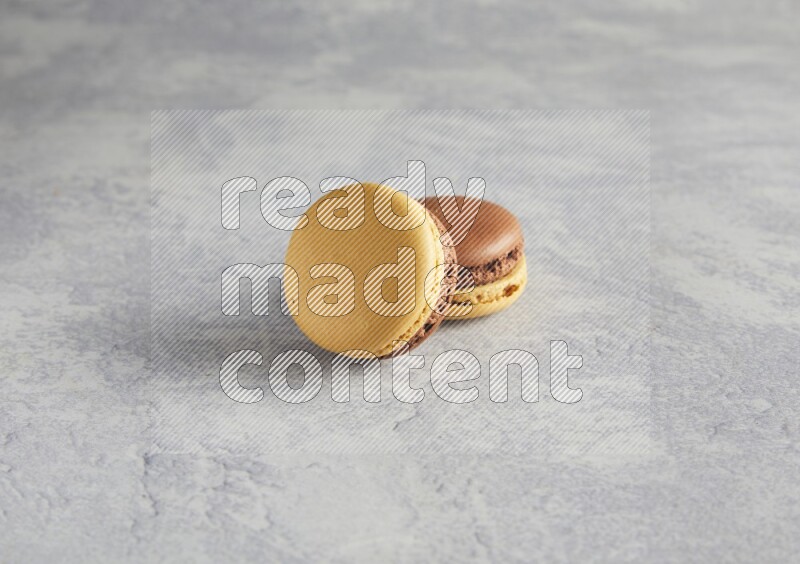 45º Shot of two Yellow and Brown Chai Latte macarons r on white  marble background