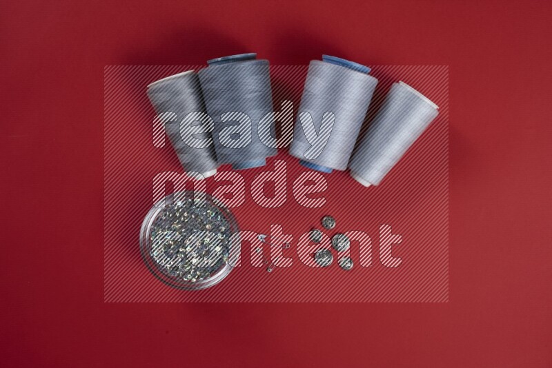 A grey collection of sewing and tailoring tools arranged on a red background