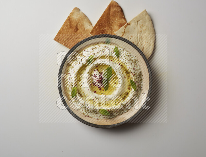 Lebnah garnished with zaater, mint & sumak in a pottery plate on a white background