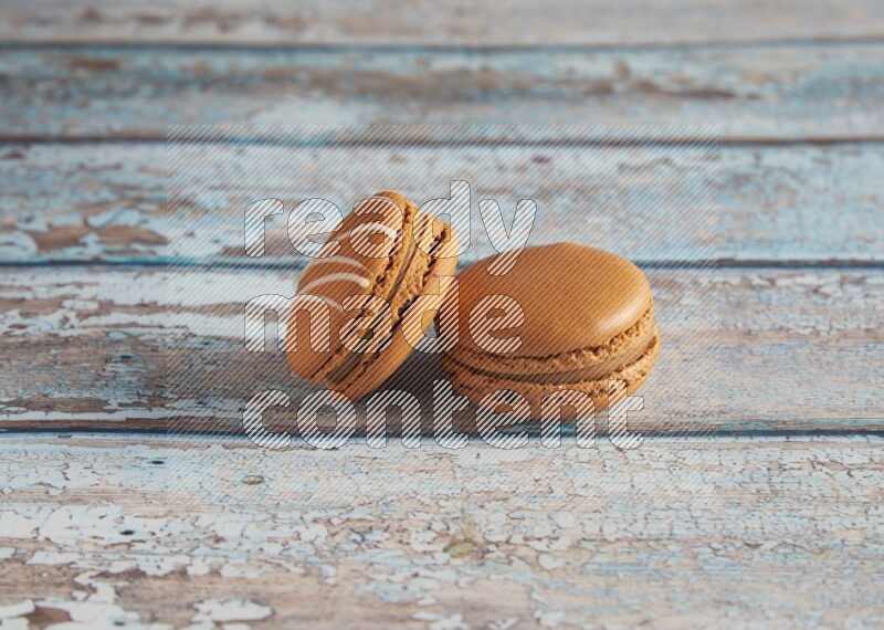 45º Shot of of two assorted Brown Irish Cream, and Brown Maple Taffy macarons  on light blue background