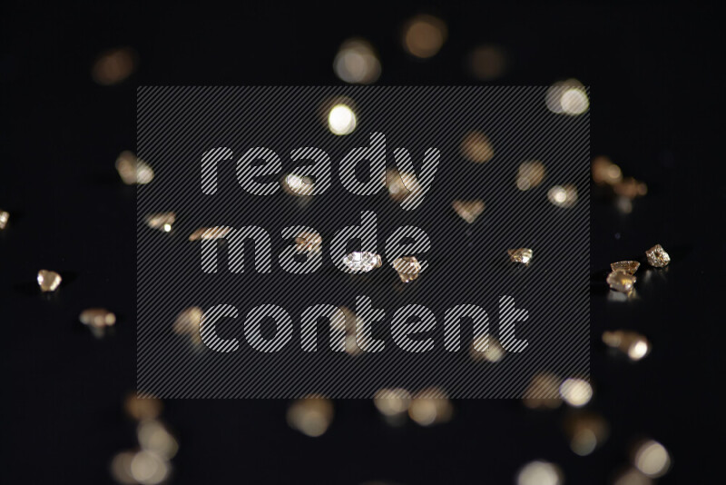 قطع زجاجية ذهبية لامعة متناثرة على خلفية سوداء