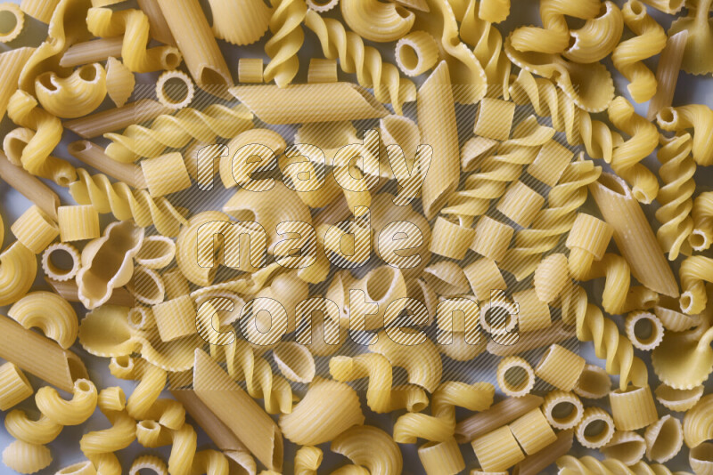 Different pasta types on light blue background