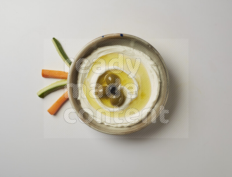 Lebnah garnished with whole olives in a grey pottery plate on a white background