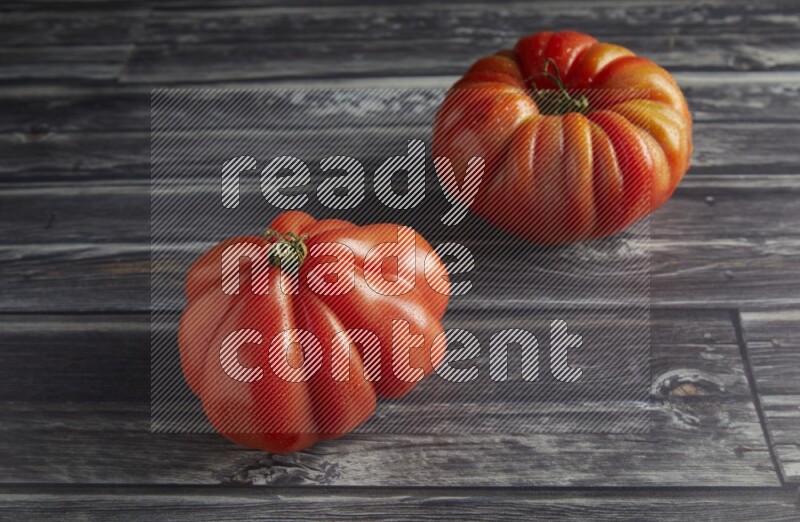 45 degree two heirloom tomato on a textured grey wooden background