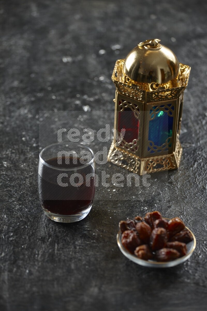 A golden lantern with different drinks, dates, nuts, prayer beads and quran on textured black background