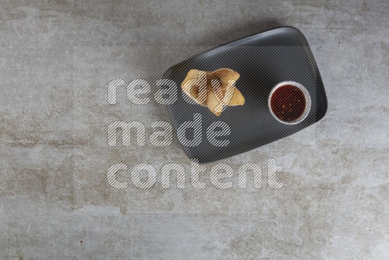 wonton cups with soy sauce ramkin on rectangle dark grey ceramic plate on grey textured counter top