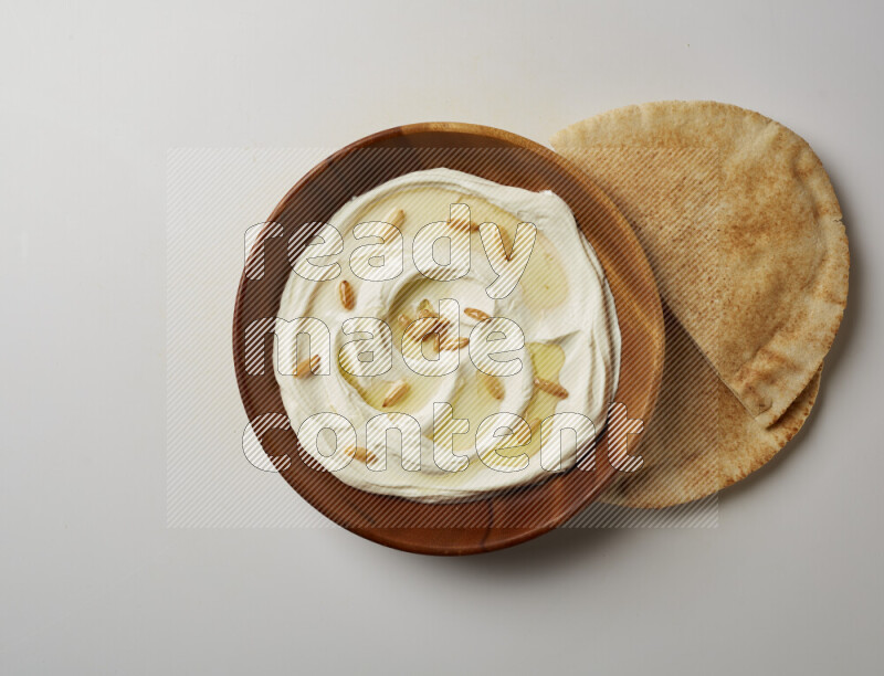Lebnah garnished with pine nuts in a wooden plate on a white background