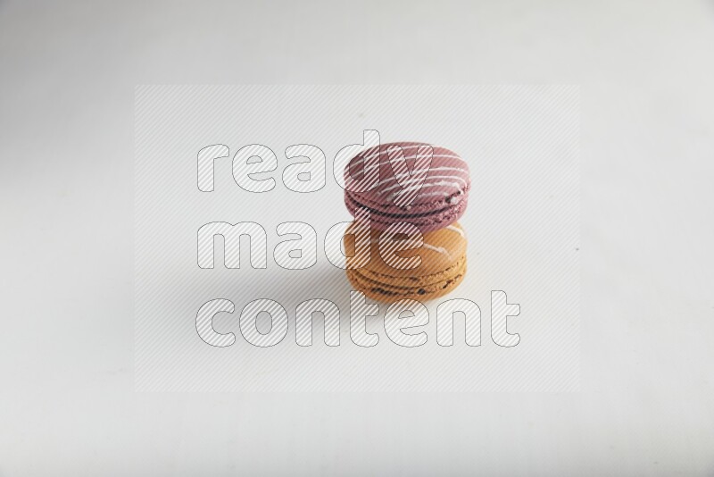 45º Shot of of two assorted Brown Irish Cream, and Red Poppy Flower macarons on white background