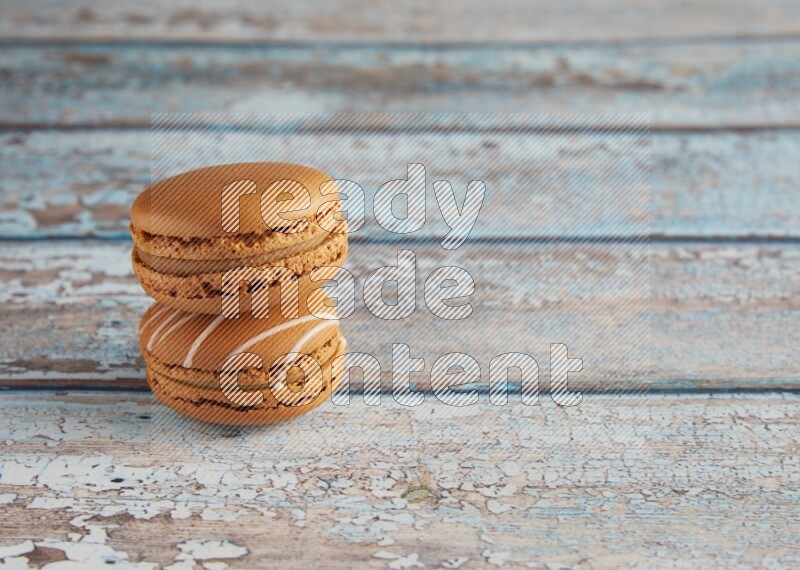 45º Shot of of two assorted Brown Irish Cream, and Brown Maple Taffy macarons  on light blue background