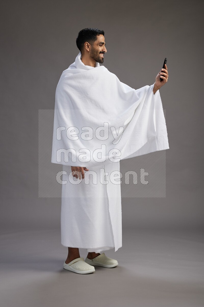 A man wearing Ehram Standing taking selfie on gray background