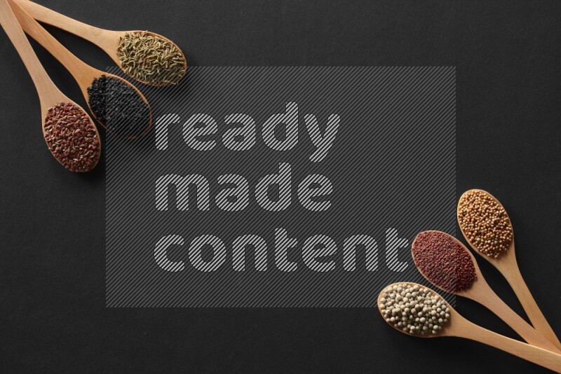 wooden spoons filled with white peppers, mustard seeds, black seeds, garden cress, cumin and flax on black flooring