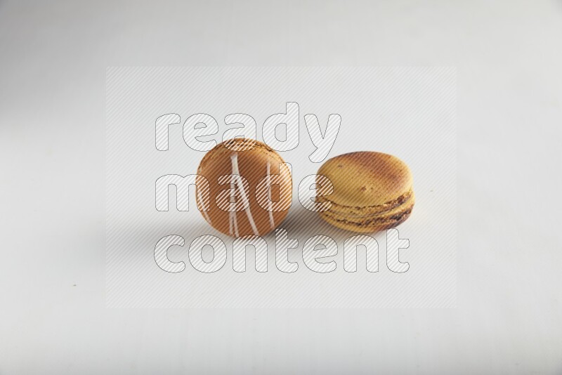 45º Shot of of two assorted Brown Irish Cream, and Yellow Crème Brulée macarons on white background