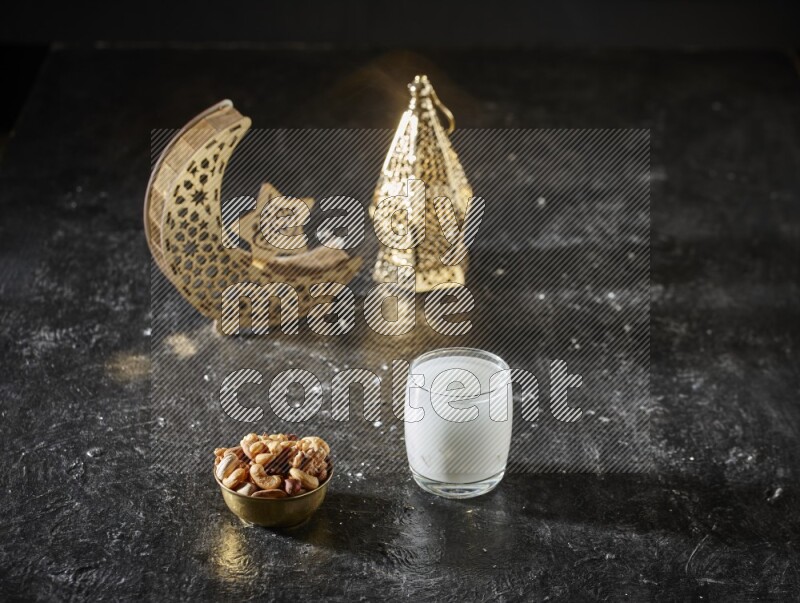 مكسرات في وعاء معدني مع السوبيا بجانب فوانيس ذهبية علي خلفية سوداء