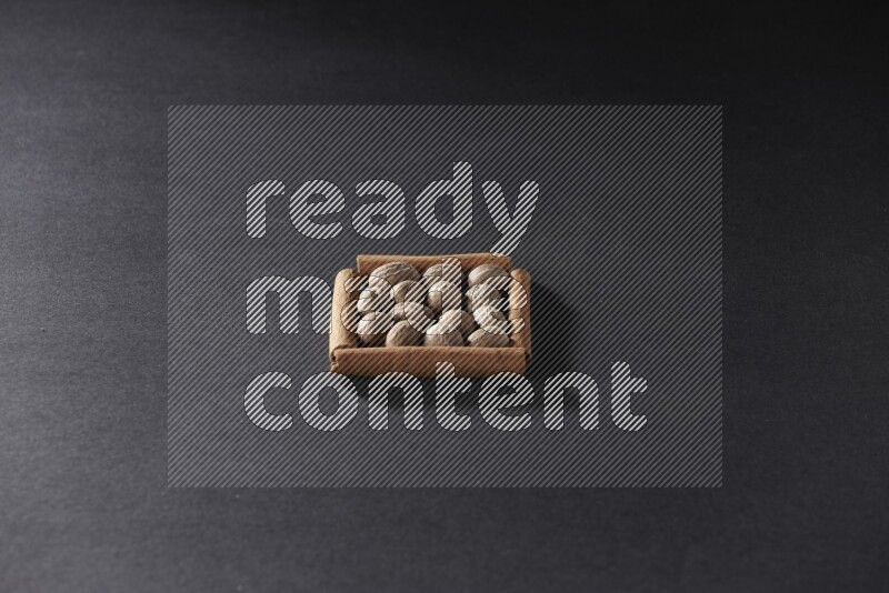 A single square of cinnamon sticks full of nutmeg on black flooring