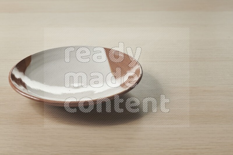 A multicolored pottery plate on light wooden background