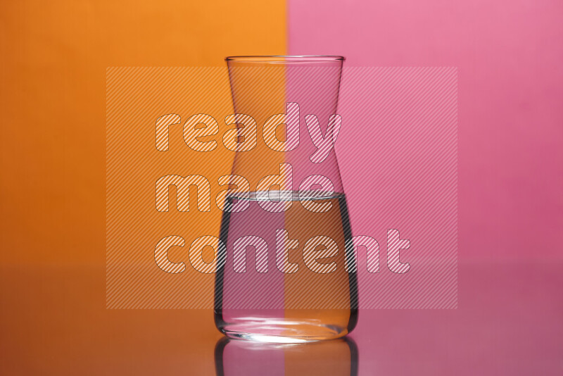 The image features a clear glassware filled with water, set against orange and pink background
