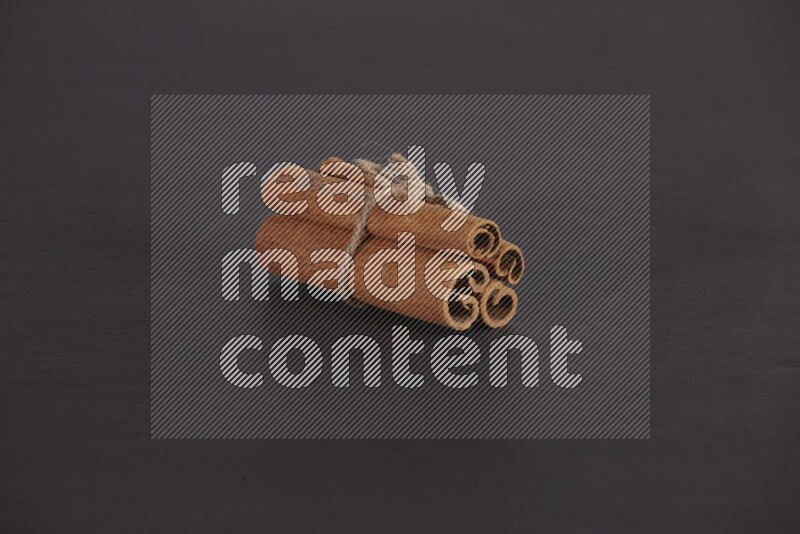 4 Cinnamon sticks stacked and bounded on black flooring