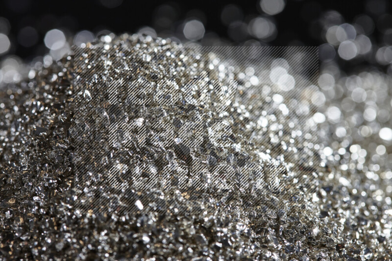 Silver shimmering fragments of glass scattered on a black background