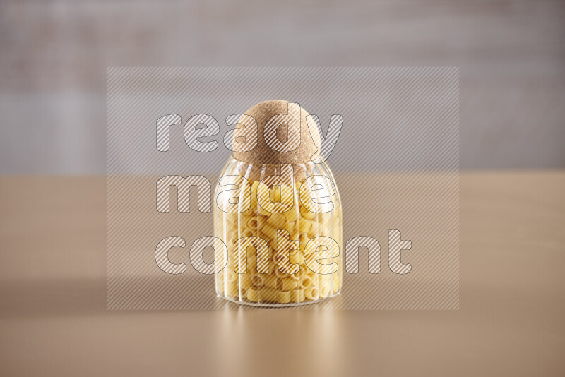Raw pasta in glass jars on beige background