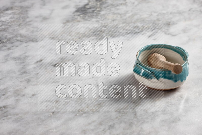 Multicolored pottery bowl with wooden honey dipper in it on grey marble background