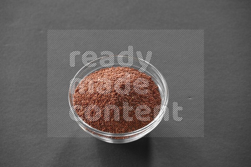 A glass bowl full of garden cress on black flooring
