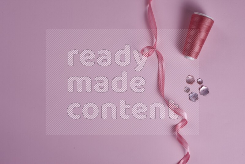 A pink collection of sewing and tailoring tools arranged on a pink background