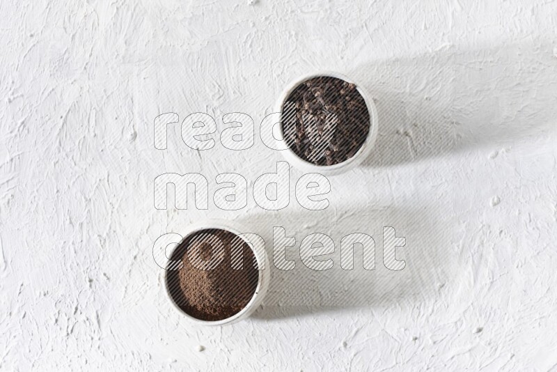 وعاءين من السيراميك بيج اللون، أحدهما مملوء بالقرنفل والآخر مملوء بالبودرة على أرضية بيضاء