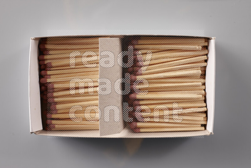 An open matchbox revealing wooden matches on a grey background