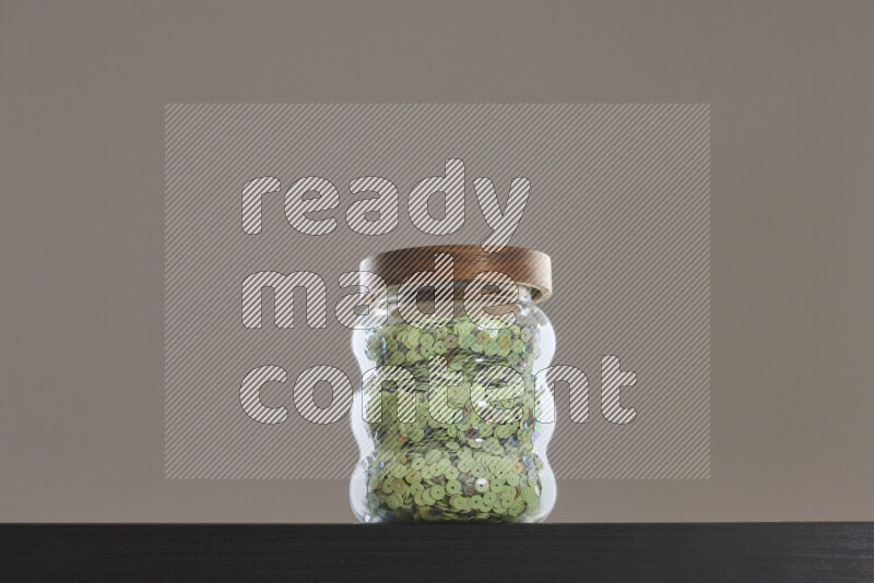Sequins in a glass jar on black background