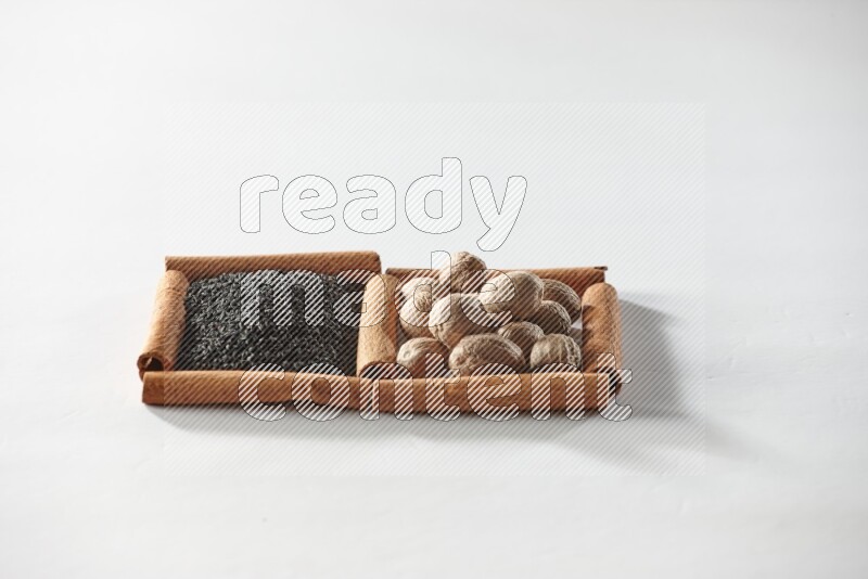 2 squares of cinnamon sticks full of black seeds and nutmeg on white flooring