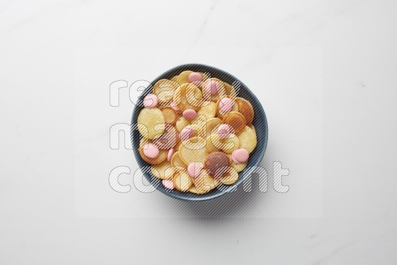 Top-view shot of pink chocolate chips cereal pancakes in a round bowl on white background