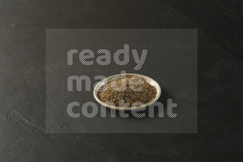 white ceramic round sauce dish filled with herbs on grey textured countertop