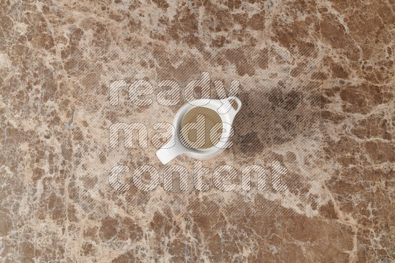 A ceramic milk jug on beige marble background