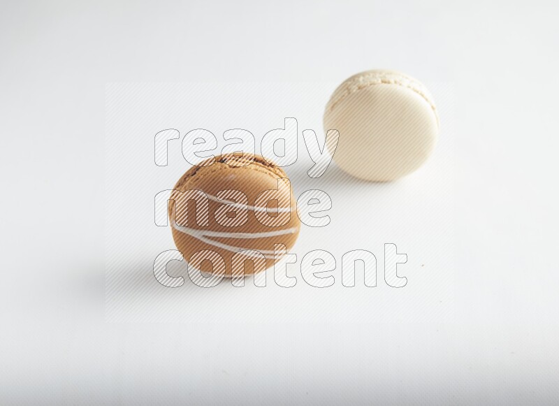 45º Shot of of two assorted Brown Irish Cream, and White Caramel fleur de sel macarons on white background