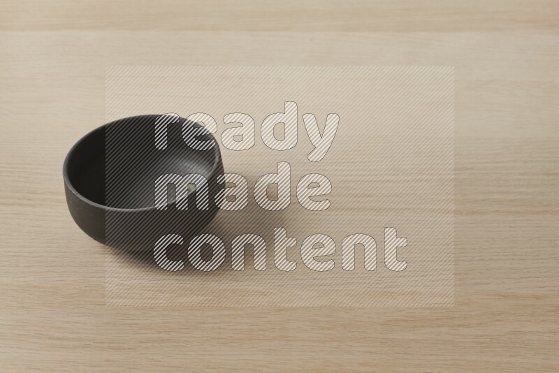 A black pottery bowl on light wooden background