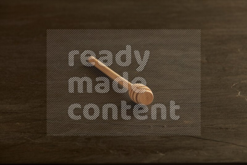 Wooden honey dipper on black slate background