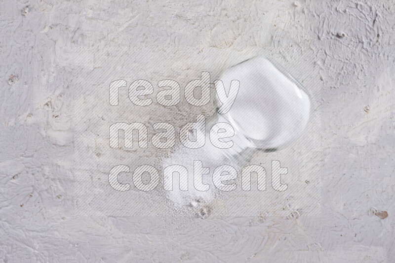 A glass jar full of fine table salt on white background