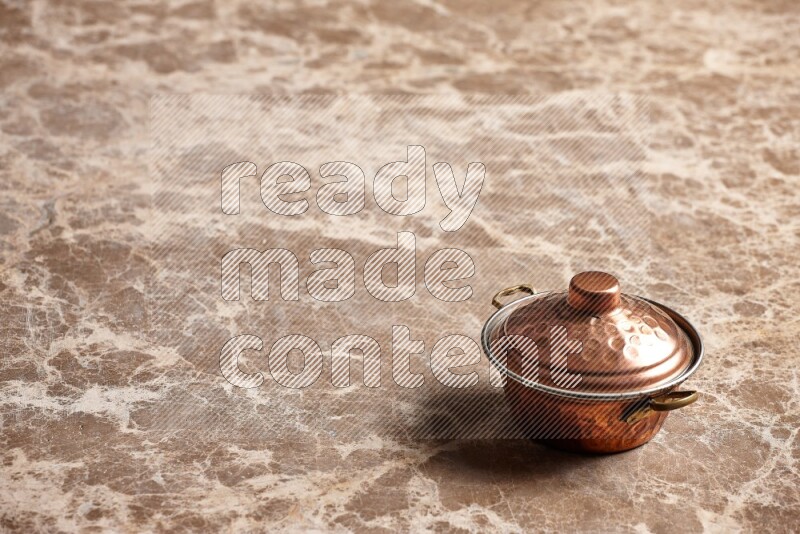 A small copper pot on beige marble background