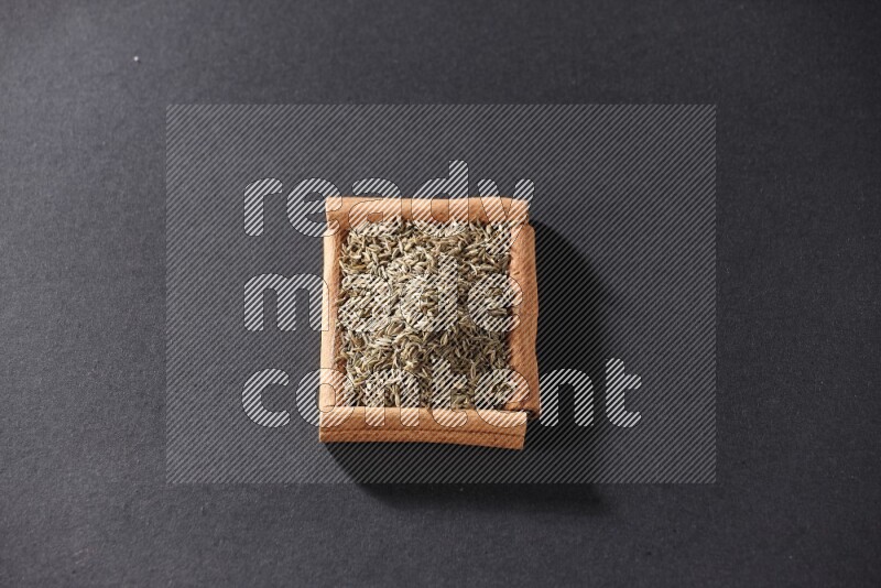A single square of cinnamon sticks full of cumin on black flooring