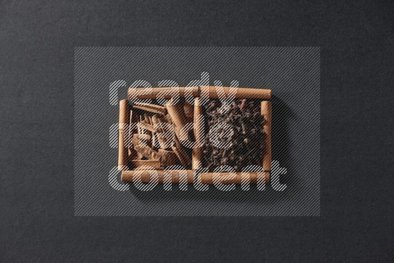 2 squares of cinnamon sticks full of cloves and cinnamon on black flooring