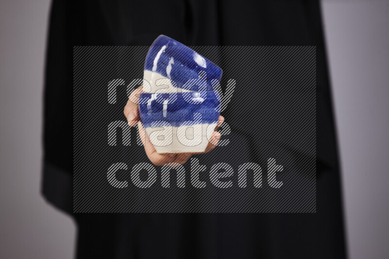 A woman in black abaya holding different pottery essentials in different positions