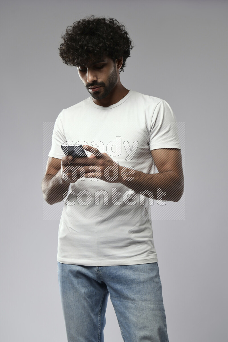 A man wearing casual standing and texting on the phone on white background