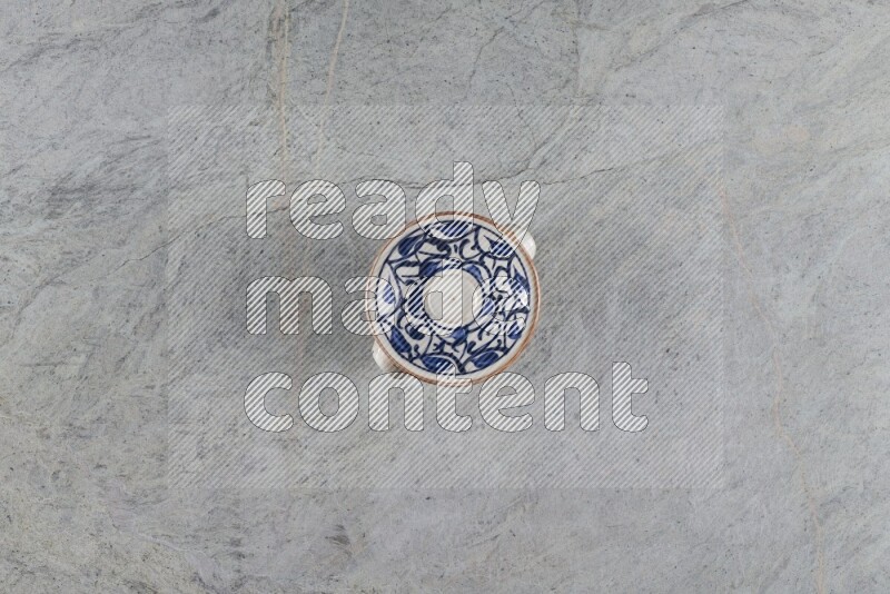 A multicolored pottery pot with its lid on grey marble background
