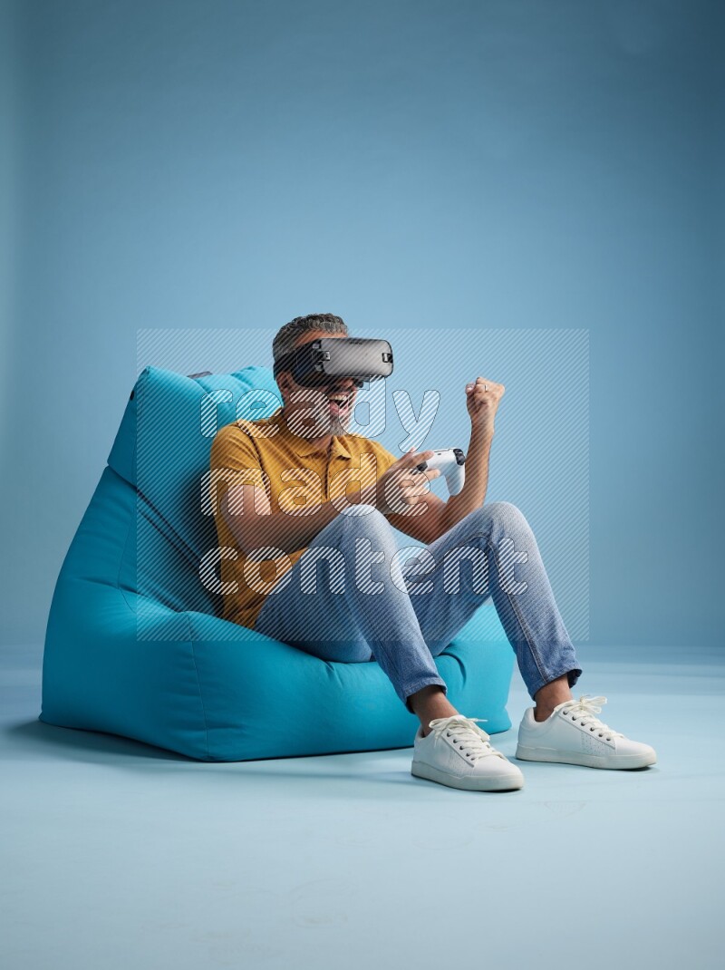 A man sitting on a blue beanbag and gaming with VR