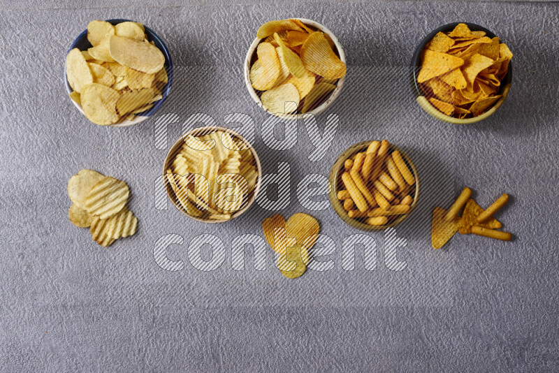 Assorted snacks in pottery bowls on grey background