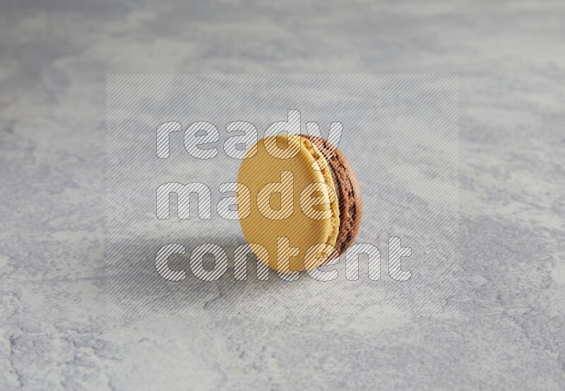 45º Shot of Yellow and Brown Chai Latte macaron on white  marble background