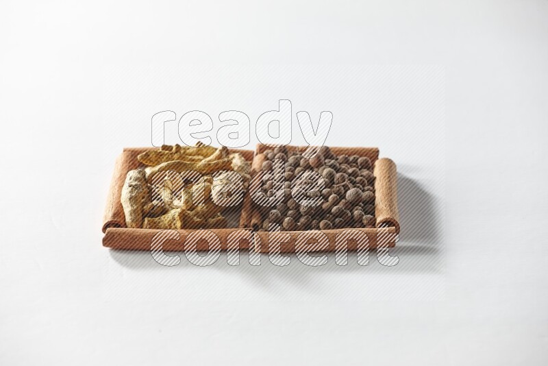 2 squares of cinnamon sticks full of allspice and turmeric fingers on white flooring